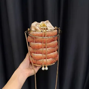 Detail of luxury gold cage bucket bag with crystal accents and pearl pendant