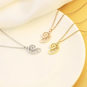Pendentifs nautile minimalistes en or, or rose et argent sur un plateau blanc