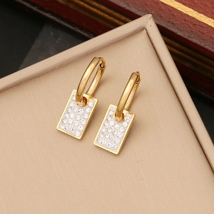 Detailed close-up of golden rectangle earrings with pavé-set zircons on a jewelry box
