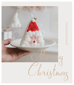 Main tenant une bougie parfumée décorative du Père Noël pour table de Noël