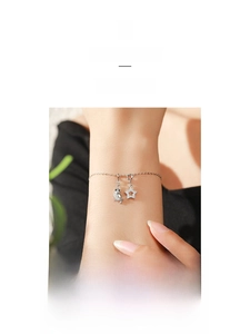 Detailed view of silver charm bracelet featuring sparkling owl and star pendants on wrist