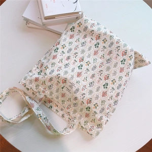 Close-up of small floral print cotton tote bag with side woven label and soft fabric texture