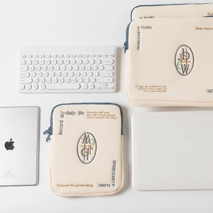 Detail of minimalist cream tablet sleeve with blue zipper and elegant embroidery