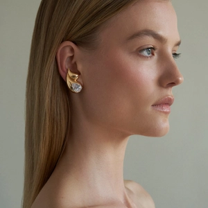 Detail view of gold double-layer teardrop earring with pear-cut zircon on model