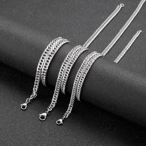 Macro view of silver flat curb link necklaces with lobster clasps on a dark textured background