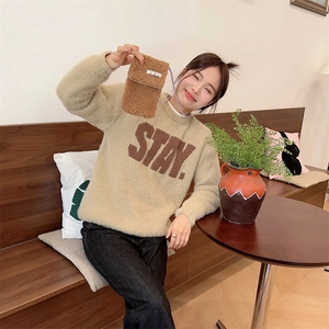Plush crossbody phone bag in brown faux fur shown in a cozy cafe setting on a model