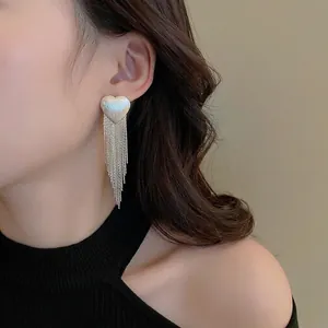 Elegant silver heart stud earrings with long metal tassel chains on a female model
