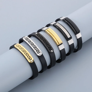 Multiple black leather bracelets with silver and gold textured metal plates on a display stand