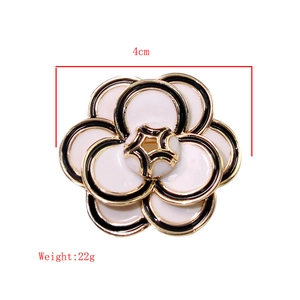 Detail view showing a 4cm camellia brooch with black and white petals and gold edges