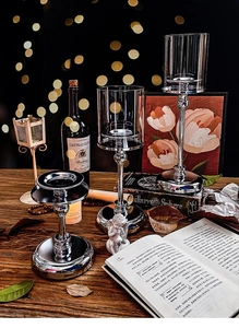Detail of silver metal candlestick set with glass covers on a wooden tabletop