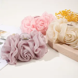 Detail of large rose chiffon hair claws in pink and beige on a decorative background