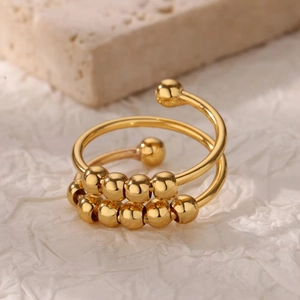 Detailed view of golden 18k spiral anxiety ring with beads on natural stone background
