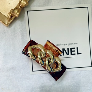 Detailed view of an amber square hair claw clip with golden chain link decoration