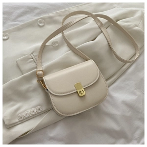 Detail shot of a cream white saddle bag with golden metal buckle on white fabric