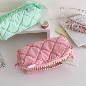 Quilted pastel pencil cases in mint green and pink with chunky zippers on a desk
