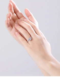 Close-up of a s925 silver moissanite engagement ring worn on a finger in soft light