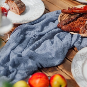 Close-up of blue-grey wrinkled cheesecloth table runner on a rustic wooden table