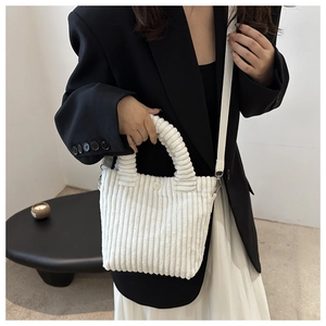 Detail of white corduroy bucket bag texture with top handle and slender strap for women