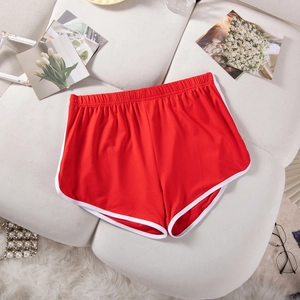 Detail of red athletic shorts with white trim placed on a white sofa for home lifestyle