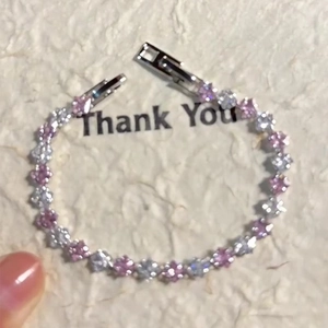 Macro detail of the floral zircon bracelet with pink petals and silver metal clasp