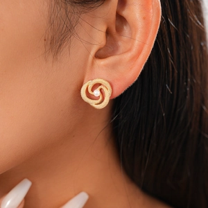 Detailed close-up of a gold twisted flower earring with a centered white pearl inlay