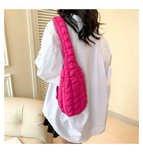 Sac bandoulière matelassé rouge rose avec texture douce de nuage porté par un mannequin