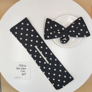 Polka dot twist hair bun maker and matching bow clip set on a clean white table