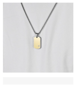 Detailed macro view of gold and silver rectangular dog tag pendant with a small diamond inlay