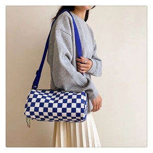 Close-up of blue and white checkerboard cylinder bag with adjustable strap