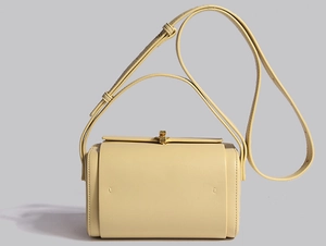 Détail d'un sac bandoulière beige en forme de boîte avec une sangle réglable