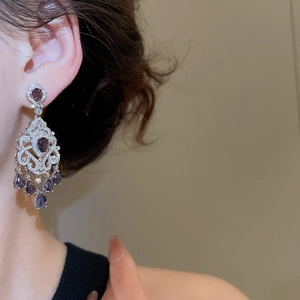 Detailed view of silver court-style earrings with purple teardrop crystals on model