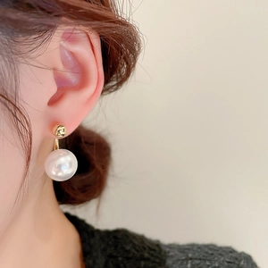 Close-up of a French style faux pearl earring with gold plating on a model's ear