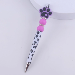 Close-up of a purple DIY beaded pen with silicone dog paw charm and rhinestone rings