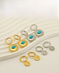 Detailed close-up of bohemian earrings with sunburst and star patterns on a wavy stand