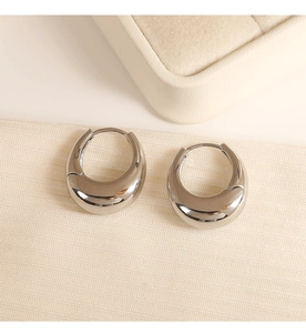 Macro shot of silver metallic hoop earrings with high polish finish on soft textured fabric