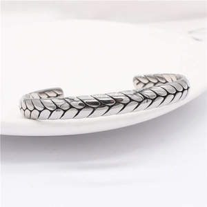 Detail of silver eagle cuff bracelet featuring intricate woven texture on a ceramic plate