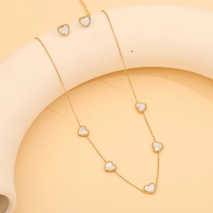 Détail d'un ensemble collier et boucles d'oreilles cœur doré avec incrustation blanche