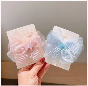 Detail of pink and blue layered chiffon bow hair clips with delicate pearl chain accents