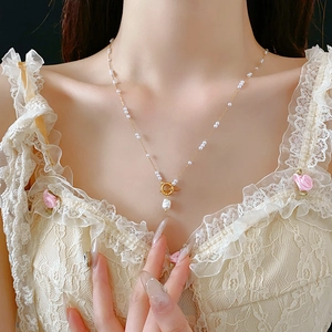 Gros plan d'un collier en or orné de perles blanches et d'un fermoir à bascule sur un mannequin