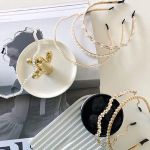 Flat lay of multiple pearl headbands and gold chain hair accessories on a white table