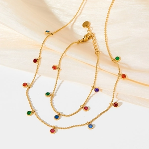 Golden double-layer station necklace with colorful round cubic zirconia on silk background