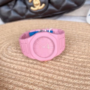 Detailed shot of a pink octagonal silicone watch resting on a textured woven mat