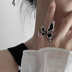 Macro detail of silver-plated butterfly ring with black enamel on woman's index finger