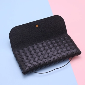 Detail of woven black leather sunglasses case showing gold button and texture