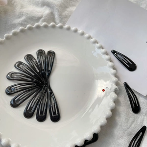 Classic black metal snap hair clips arranged neatly on a white decorative tray