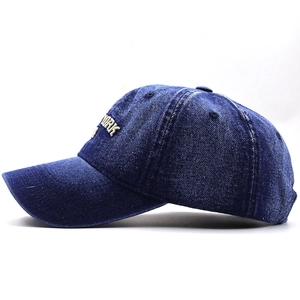 Close-up of side embroidery on a navy washed denim baseball cap with white YORK lettering