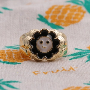 Macro shot of gold-plated flower ring with a white smiley face center and petals