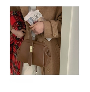Detail of vintage dark brown faux leather doctor bag with golden metal clasp and top handle