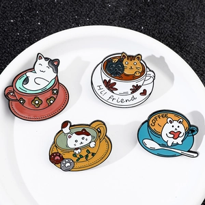 Close-up of four cute cartoon cat and coffee cup enamel pins on a white tray