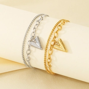 Close-up of double-layer heart charm bracelets in gold and silver with hammered texture